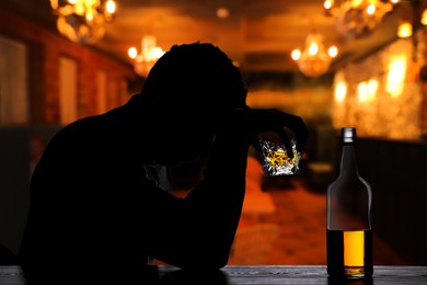 Image of Silhouette of addicted man with alcoholic drink in bar