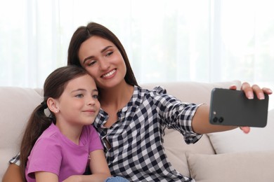 Photo of Happy mother and daughter taking selfie together at home. Single parenting