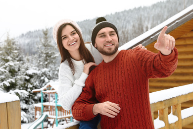 Photo of Happy couple near snowy wooden railing outdoors. Winter vacation