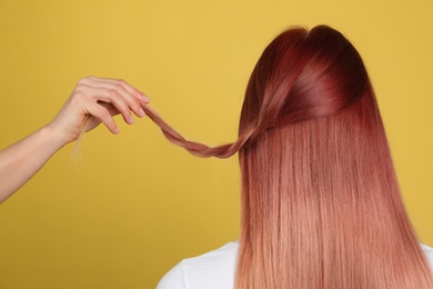 Woman with bright dyed hair on yellow background, back view