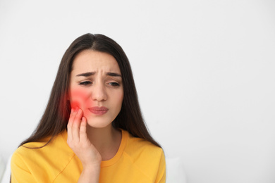 Young woman suffering from toothache on white background