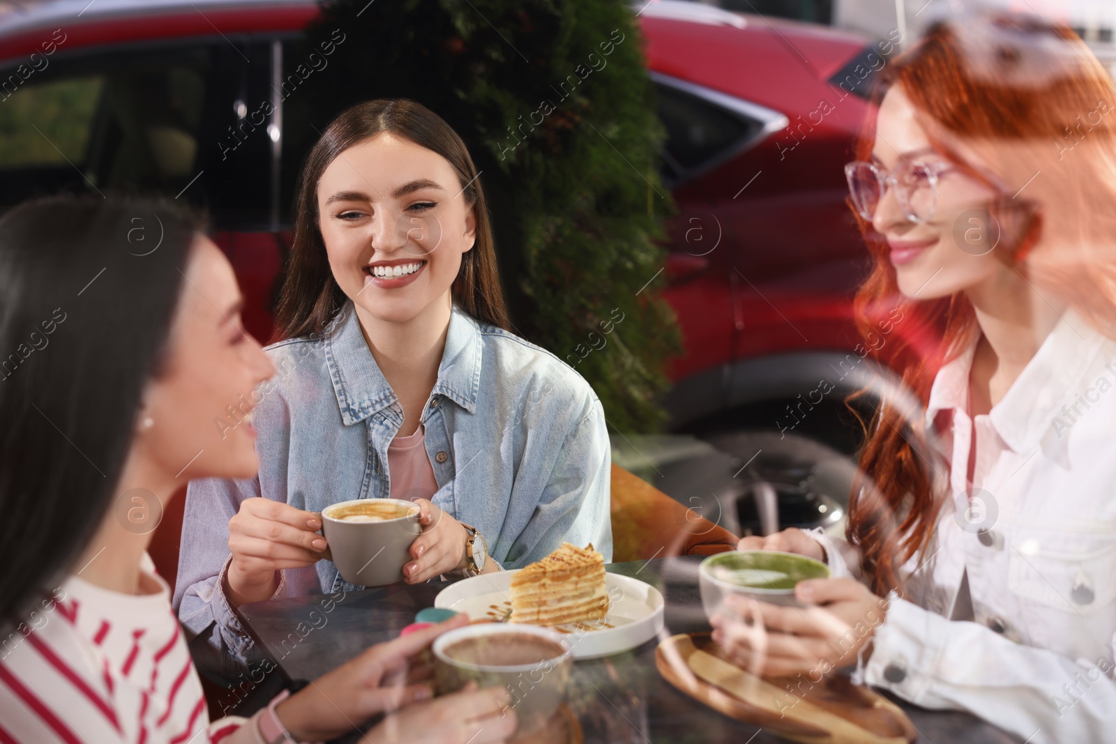 Photo of Happy friends spending time together in cafe, view through window