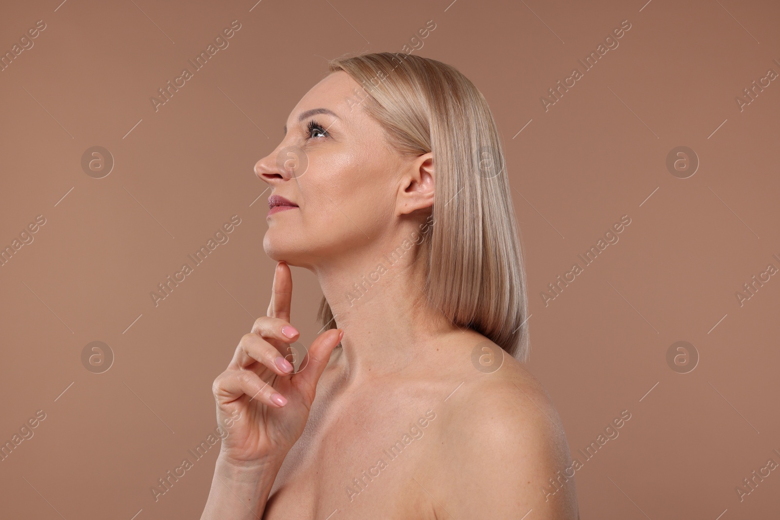 Photo of Beautiful woman touching her neck on beige background