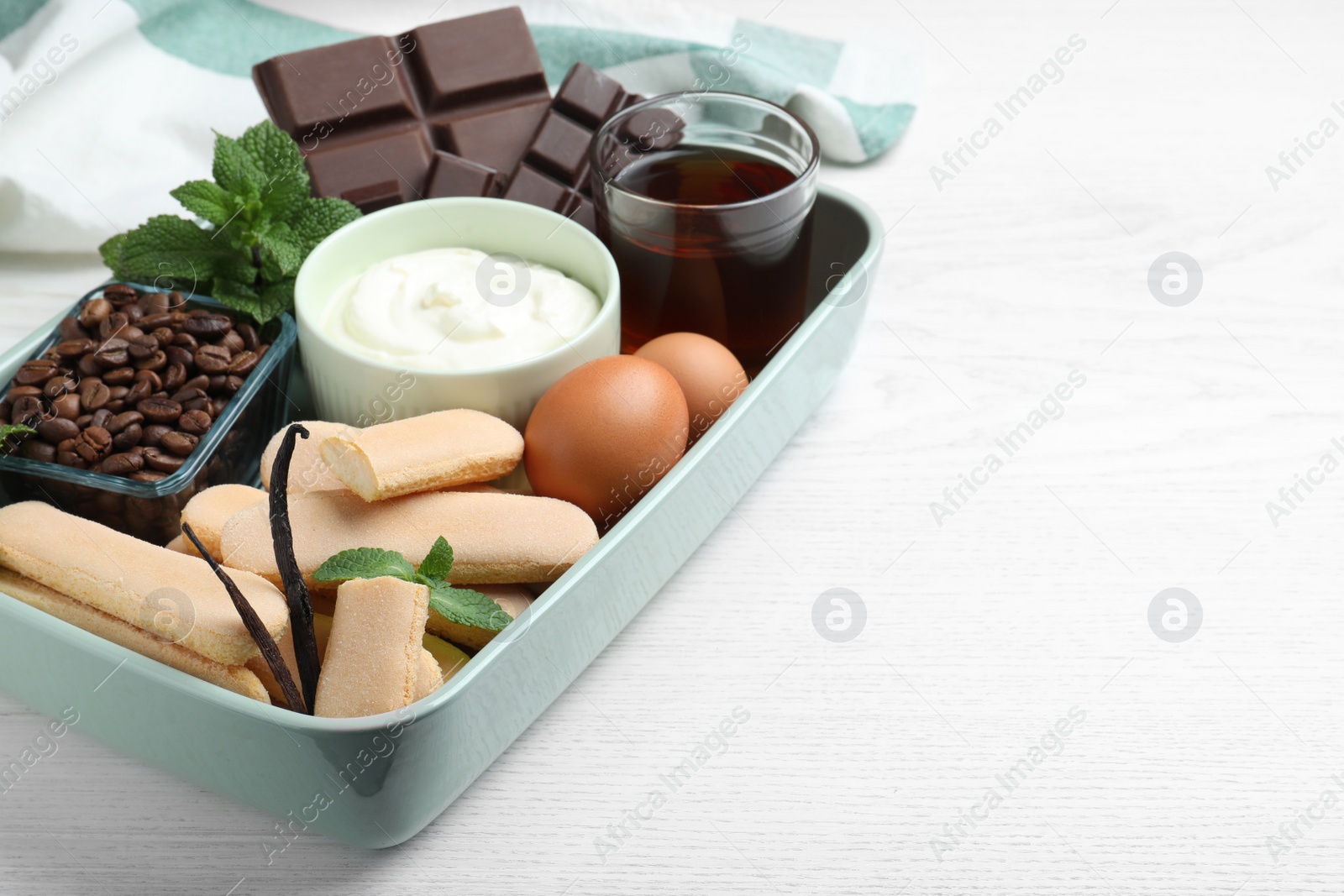 Photo of Baking dish with tiramisu ingredients on white wooden table, space for text