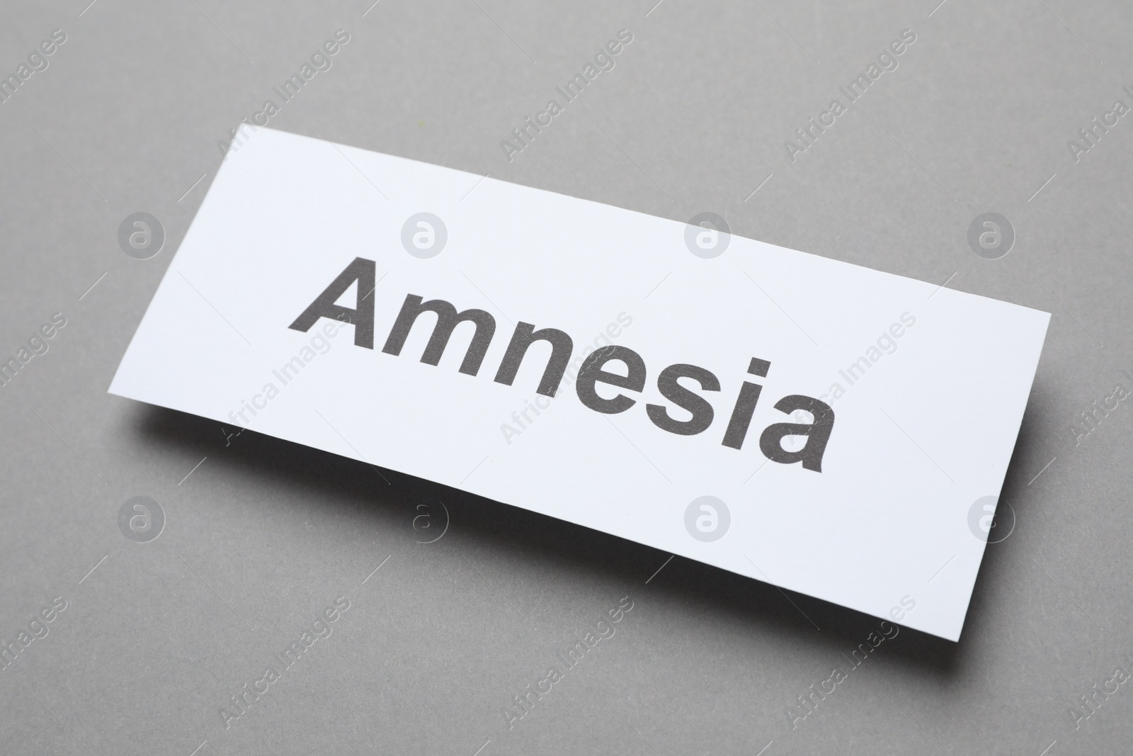 Photo of Card with word Amnesia on grey background, above view