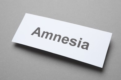 Photo of Card with word Amnesia on grey background, above view