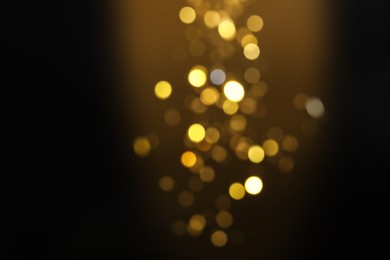 Blurred view of golden lights on black background. Bokeh effect