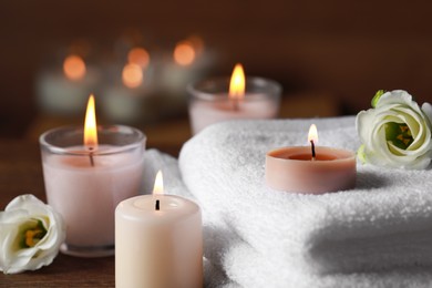 Photo of Beautiful spa composition with burning candles and flowers on wooden table, closeup