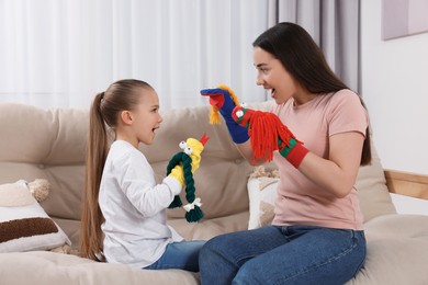 Photo of Emotional mother and daughter playing with funny sock puppets together at home