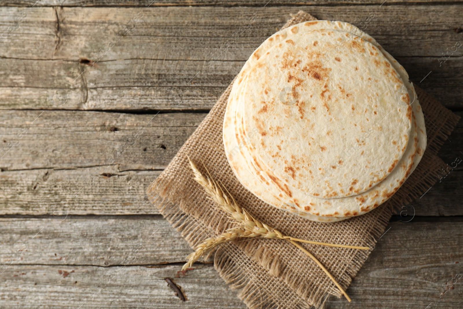 Photo of Tasty homemade tortillas and spikes on wooden table, top view. Space for text