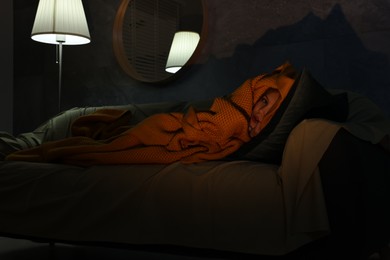 Little girl hiding from monster in blanket on sofa at night
