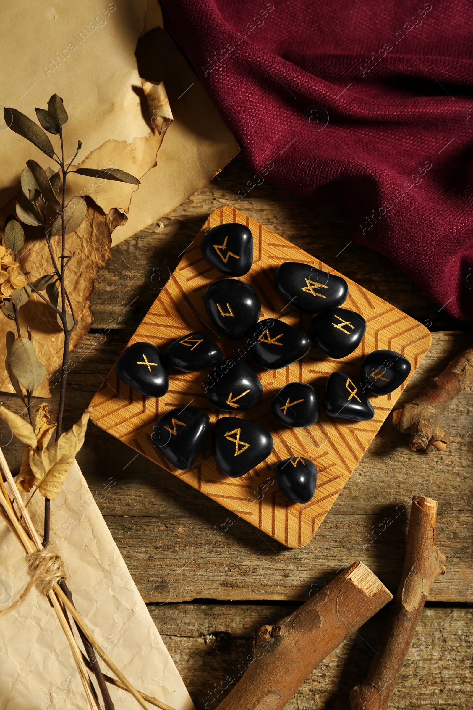 Photo of Composition with black rune stones and dried plants on wooden table, flat lay