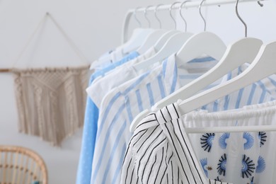 Photo of Rack with stylish hanging clothes in dressing room