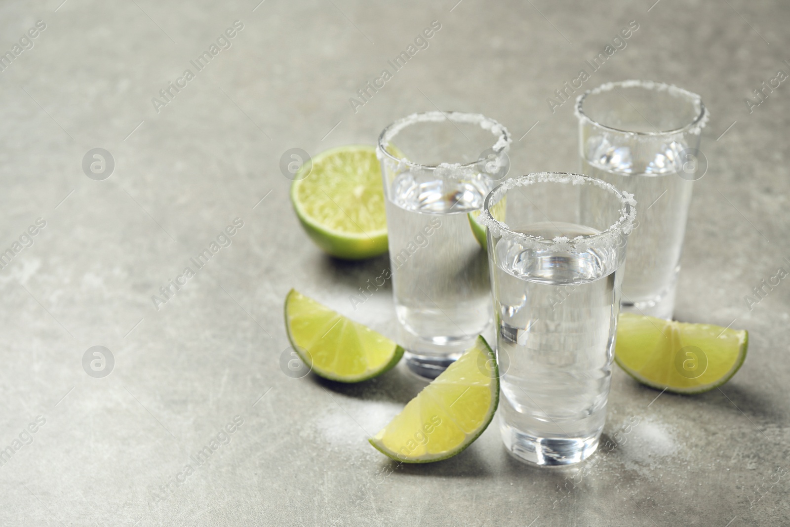 Photo of Mexican Tequila shots with salt and lime slices on grey table