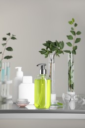 Photo of Many containers and glass tubes with leaves on metal table against light grey background