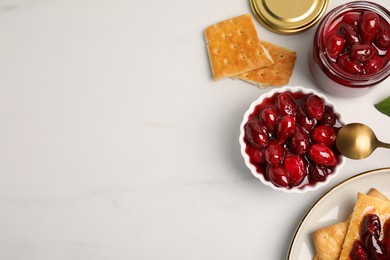 Photo of Delicious dogwood jam with berries and crispy crackers on white table, flat lay. Space for text