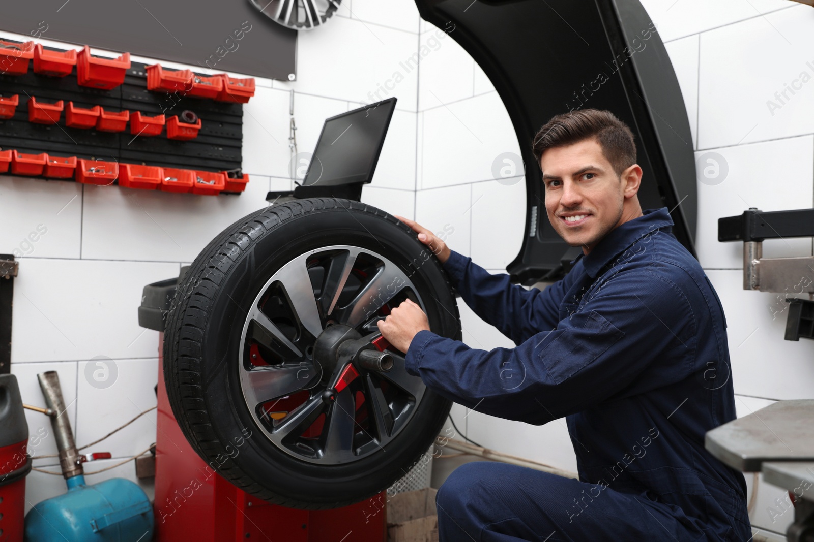 Photo of Man working with wheel balancing machine at tire service