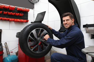 Man working with wheel balancing machine at tire service