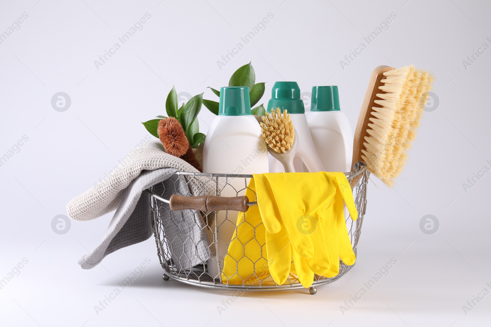 Photo of Set of different cleaning supplies in basket on white background