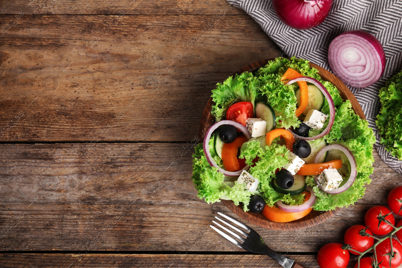 Photo of Tasty fresh Greek salad on wooden table, flat lay. Space for text