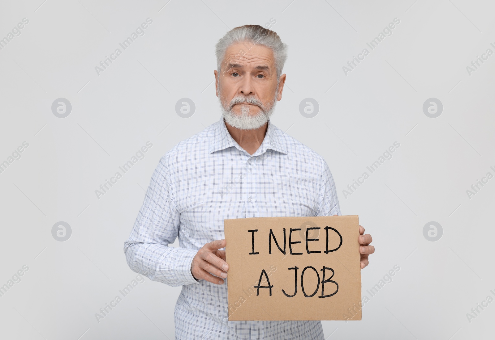 Photo of Unemployed senior man holding cardboard sign with phrase I Need A Job on white background