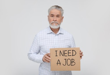 Photo of Unemployed senior man holding cardboard sign with phrase I Need A Job on white background