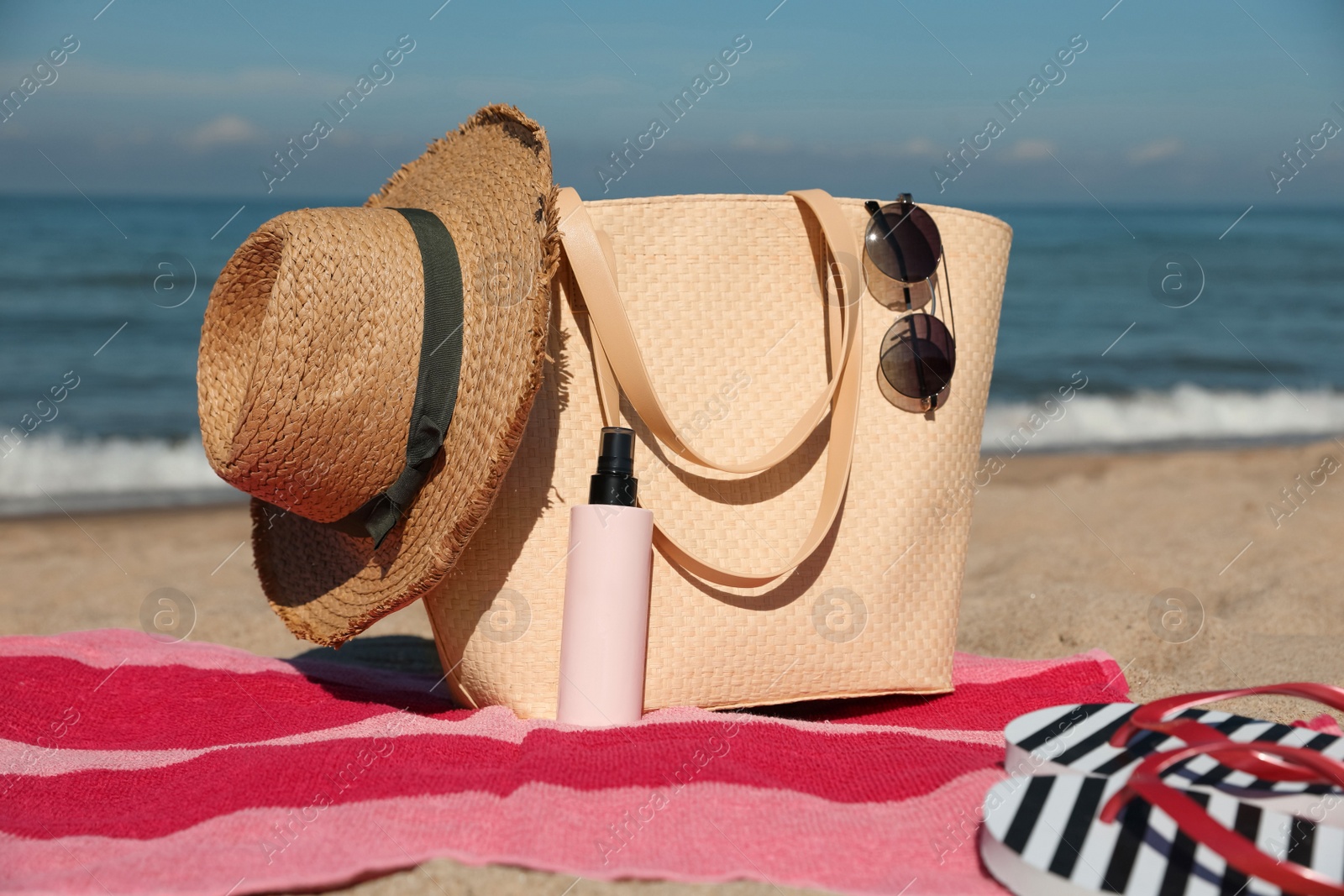 Photo of Straw hat, bag and other beach items on sandy seashore