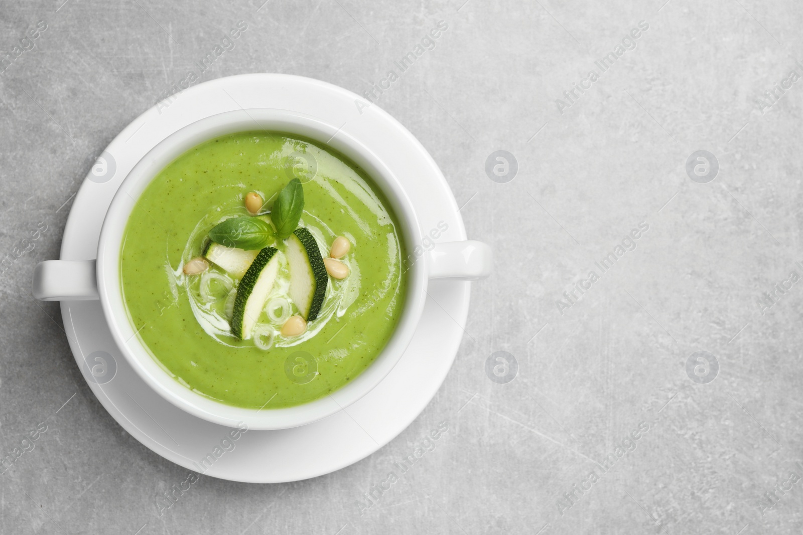 Photo of Tasty homemade zucchini cream soup on grey table, top view. Space for text