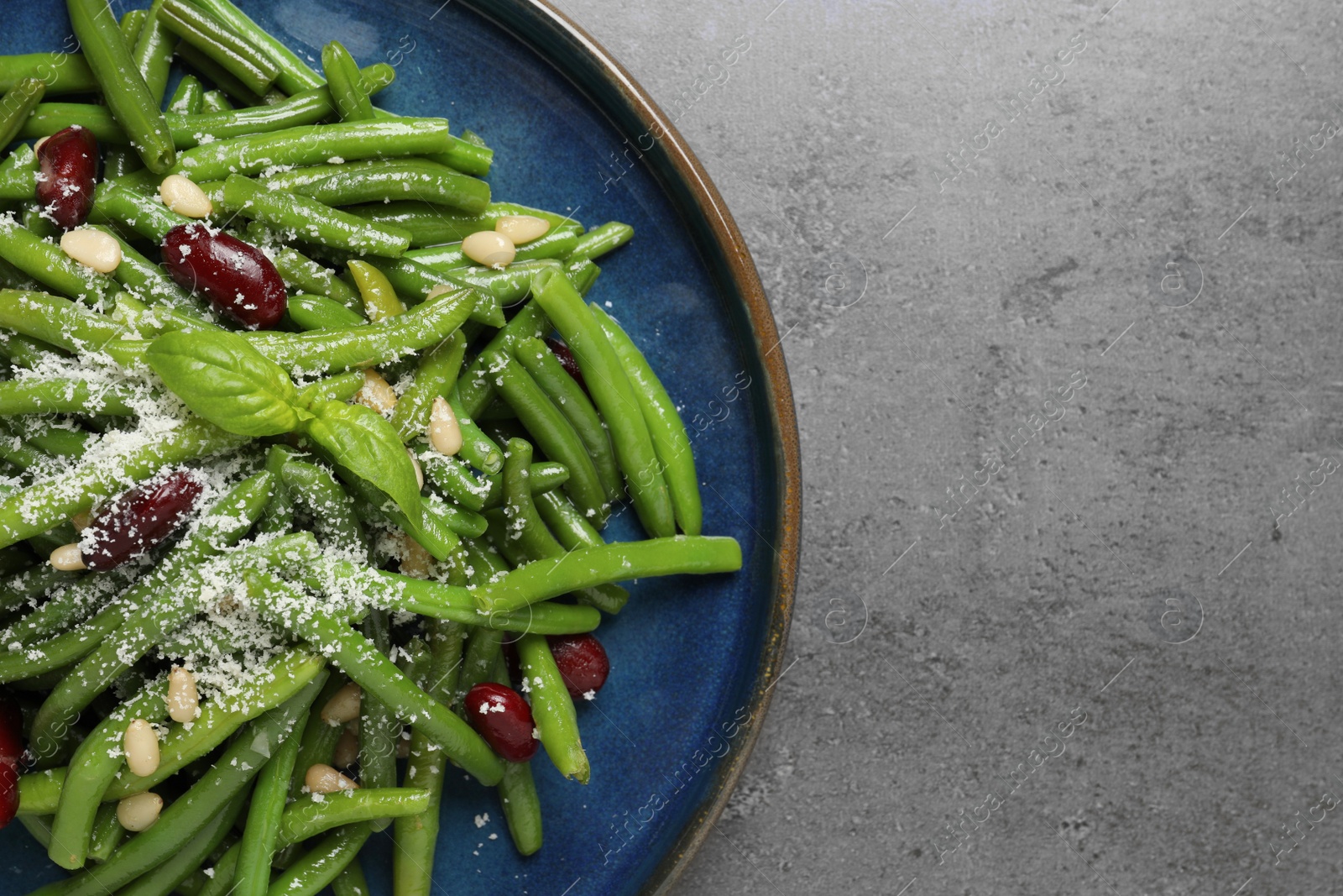 Photo of Plate of tasty salad with green beans on grey table, top view. Space for text