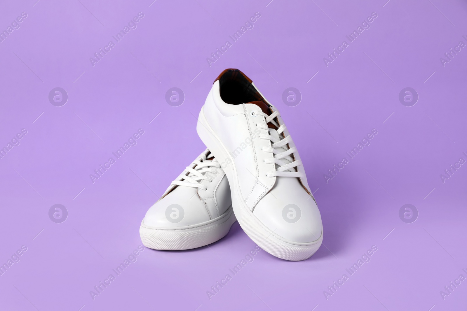 Photo of Pair of stylish white sneakers on violet background
