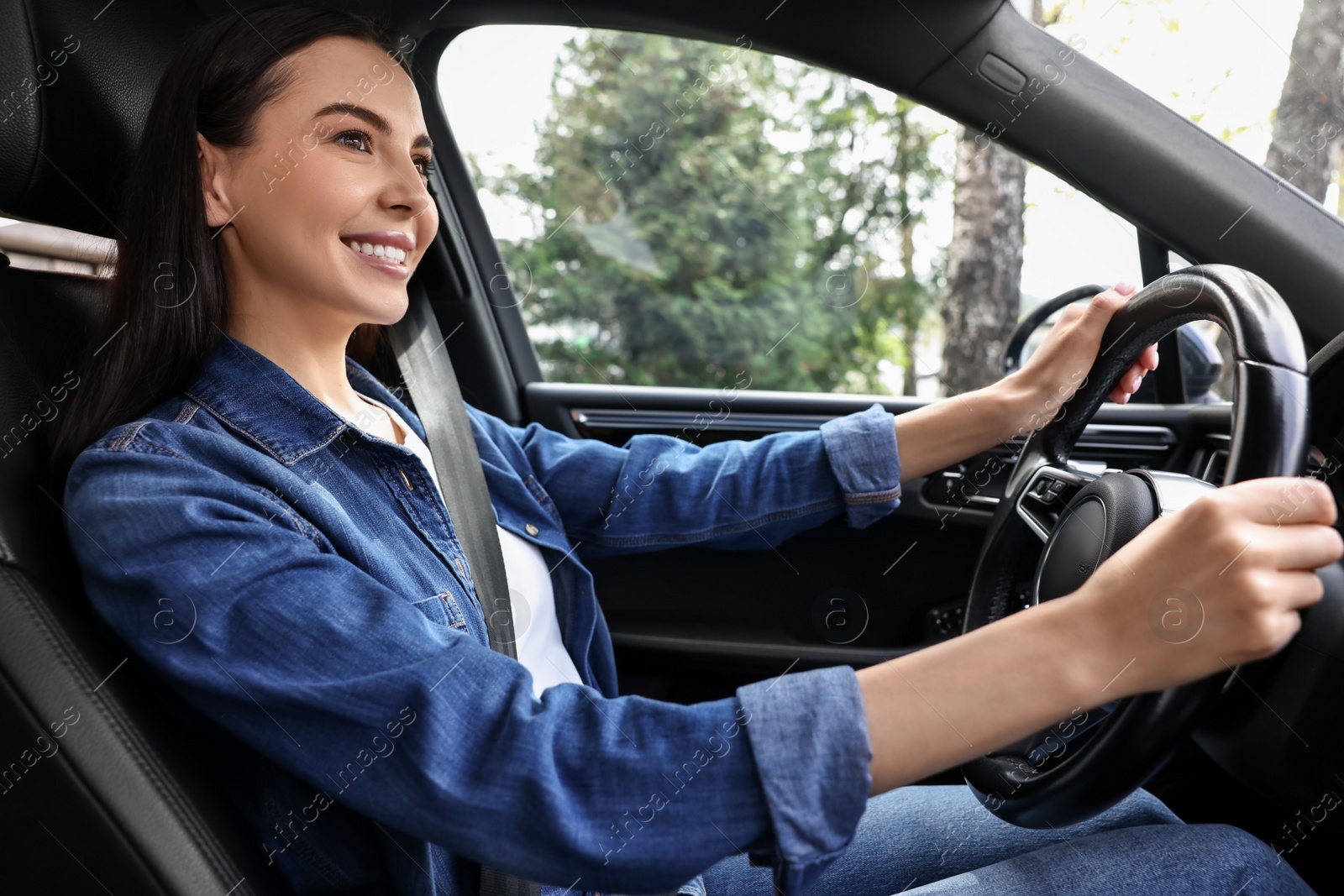 Photo of Woman with seatbelt holding steering wheel while driving her car