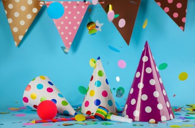 Colorful party hats and other festive items on light blue background