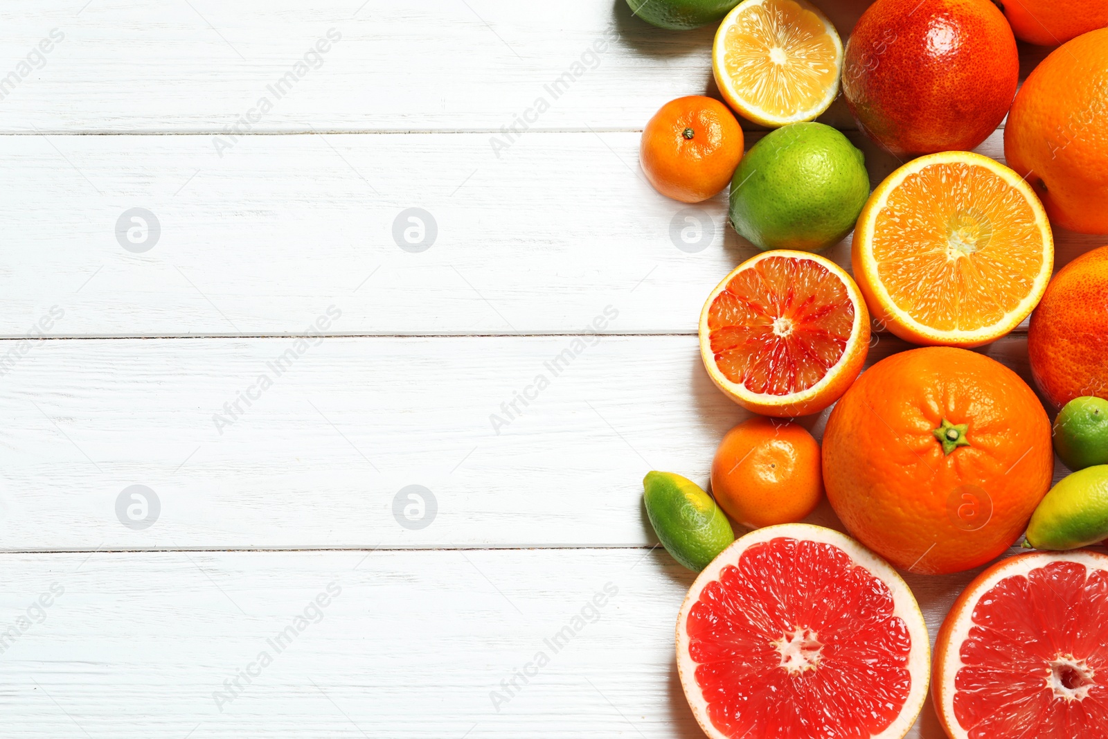 Photo of Flat lay composition with different citrus fruits and space for text on white wooden background