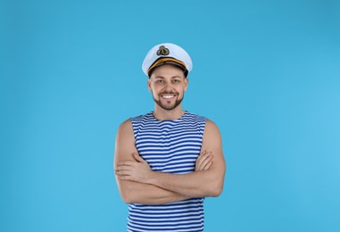 Photo of Happy sailor wearing cap on light blue background