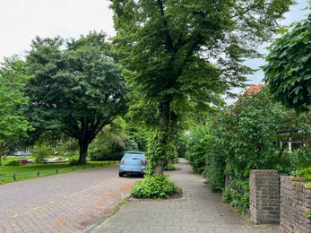 Photo of Beautiful view of city street with parked car on spring day