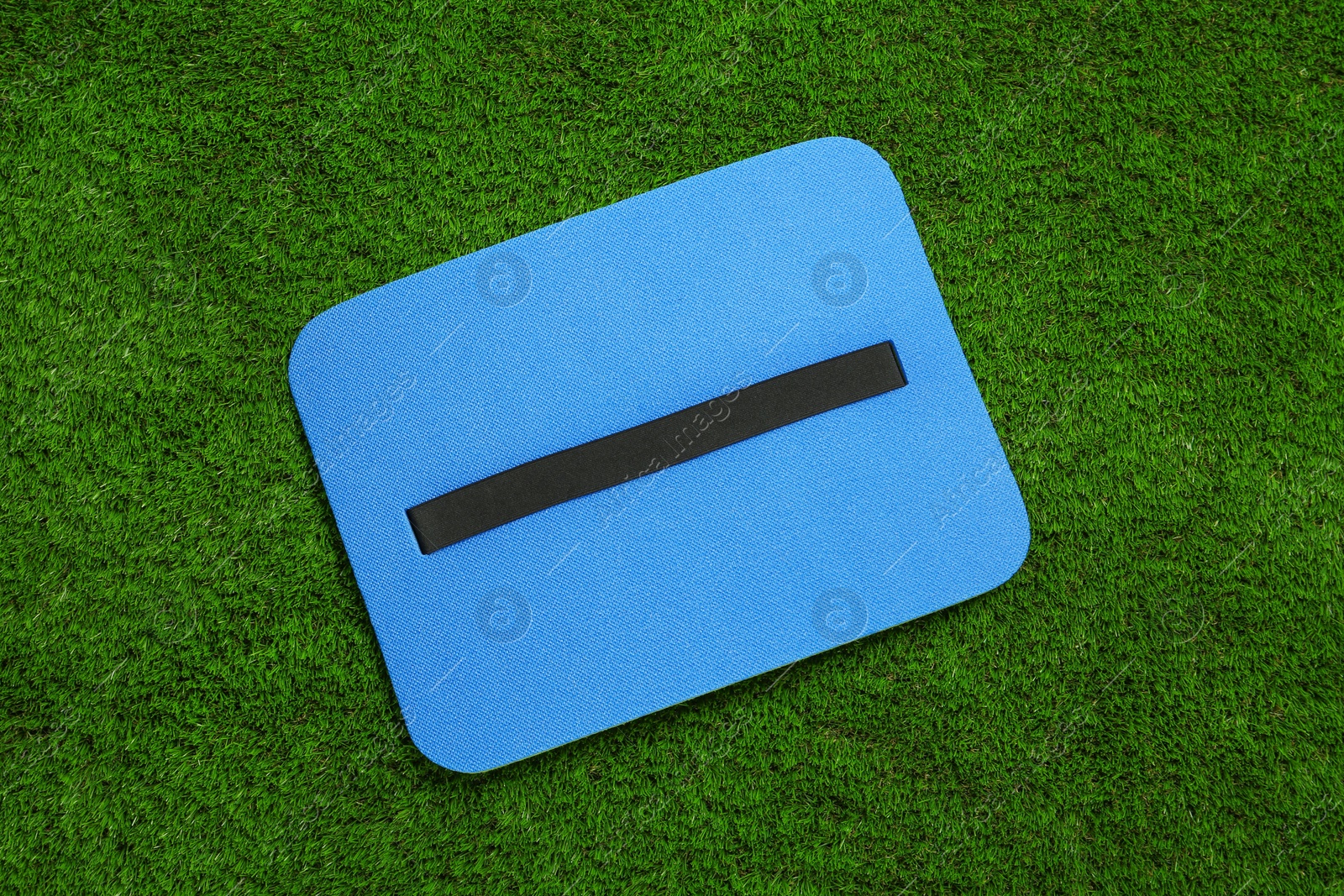 Photo of Blue foam seat mat for tourist on green grass, top view