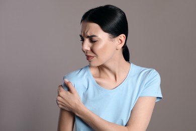 Photo of Woman suffering from shoulder pain on beige background