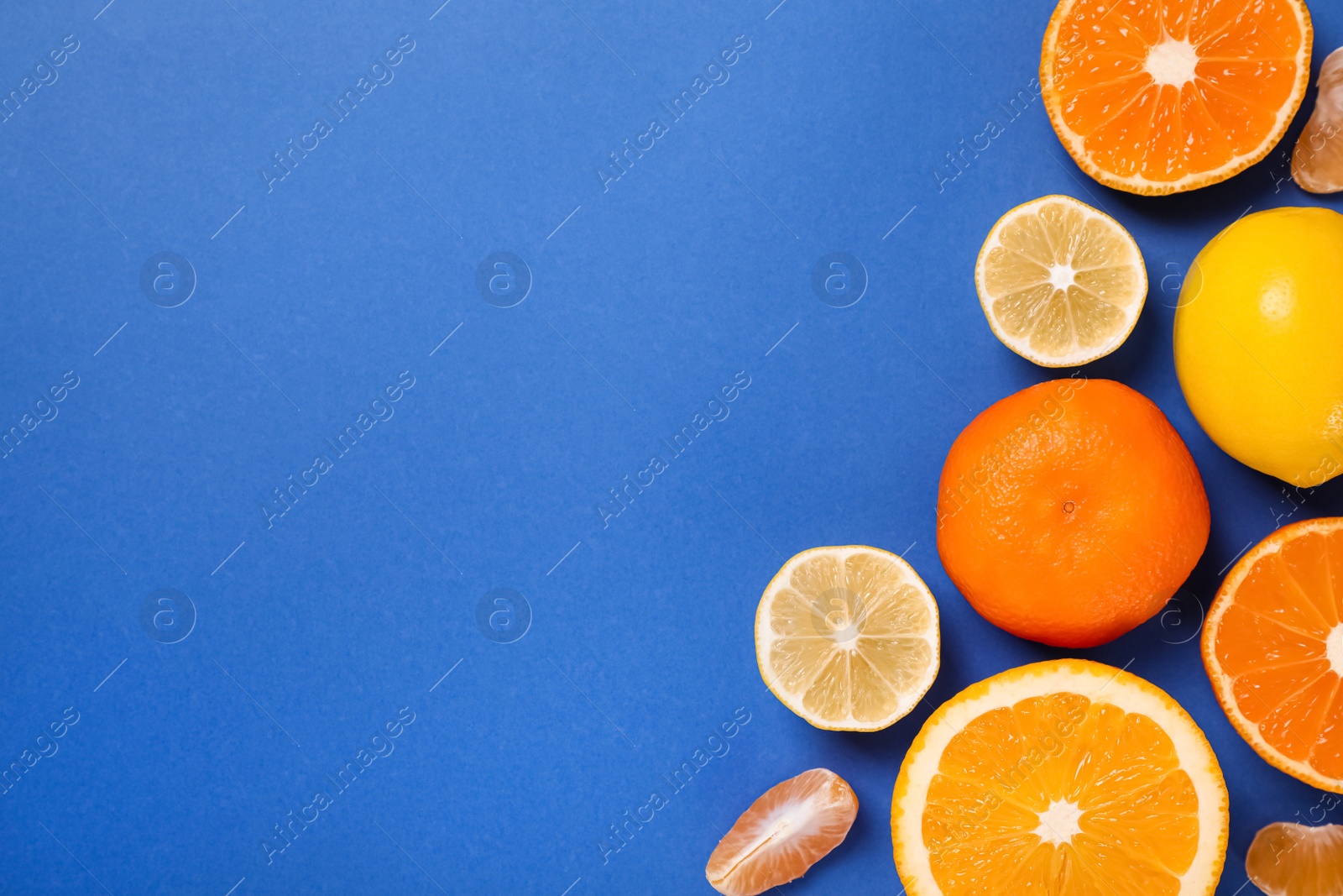 Photo of Many fresh citrus fruits on blue background, flat lay. Space for text