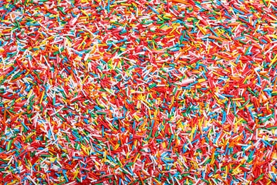 Photo of Bright colorful sprinkles as background, top view. Confectionery decor