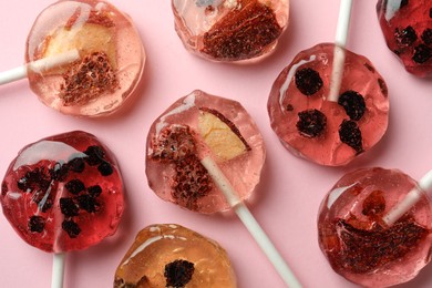 Photo of Sweet colorful lollipops with berries on pink background, flat lay