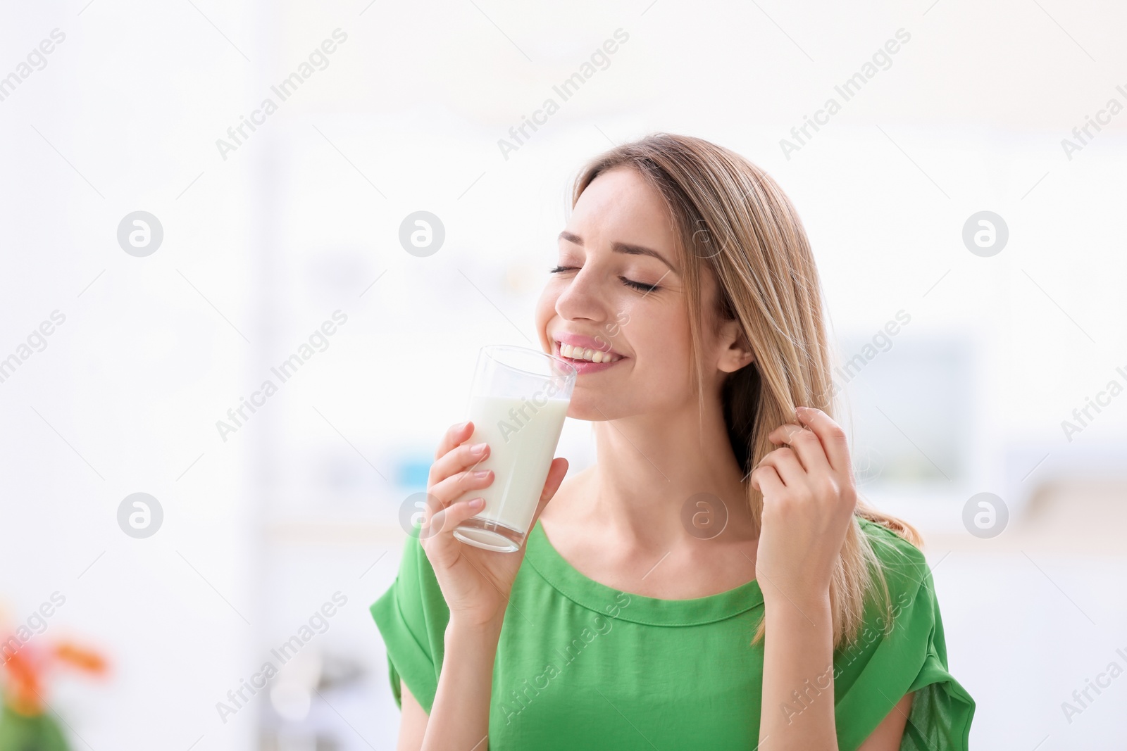 Photo of Beautiful young woman drinking milk at home