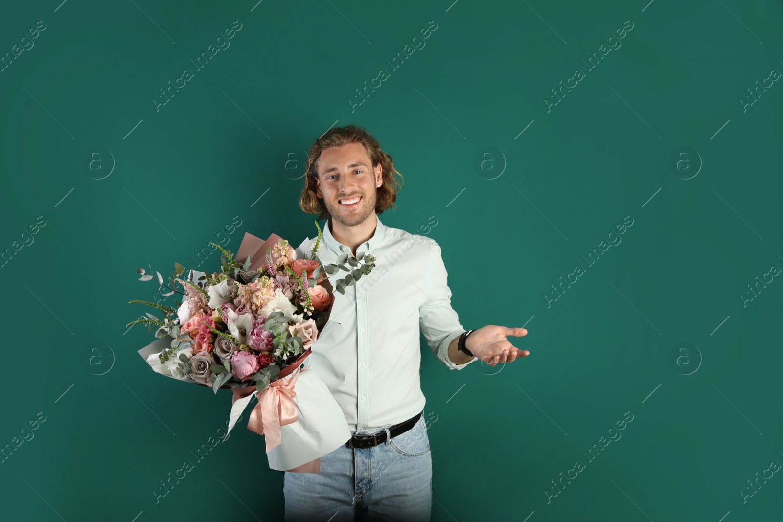 Photo of Young handsome man with beautiful flower bouquet on green background