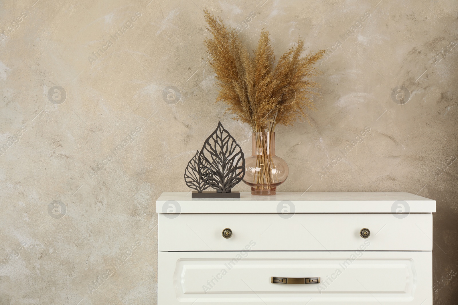 Photo of Modern chest of drawers with decor near beige wall. Space for text