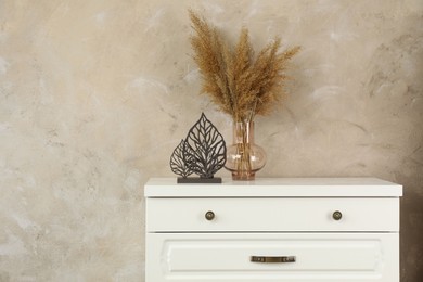 Modern chest of drawers with decor near beige wall. Space for text