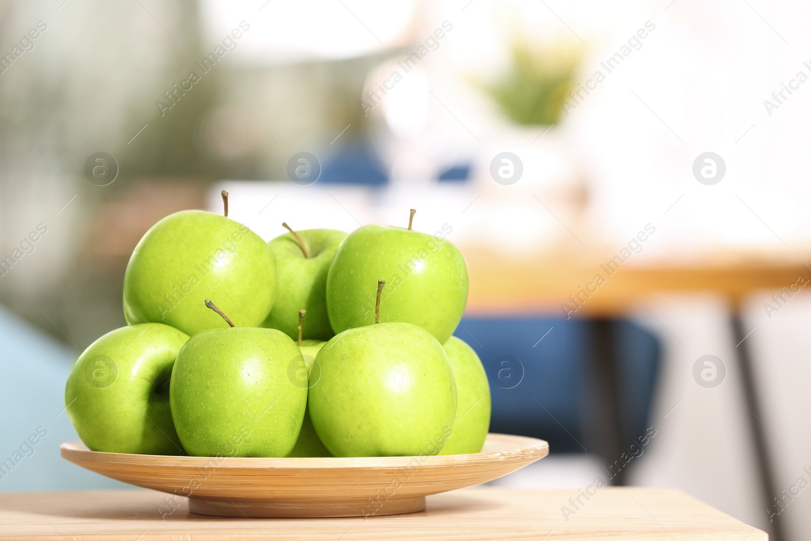 Photo of Plate with sweet green apples on table in room, space for text