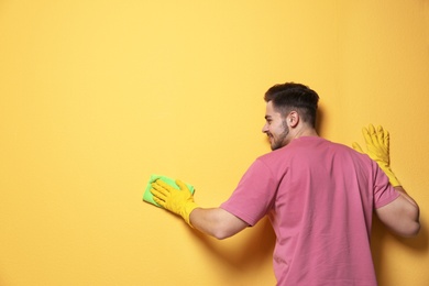 Photo of Man cleaning color wall with rag. Space for text