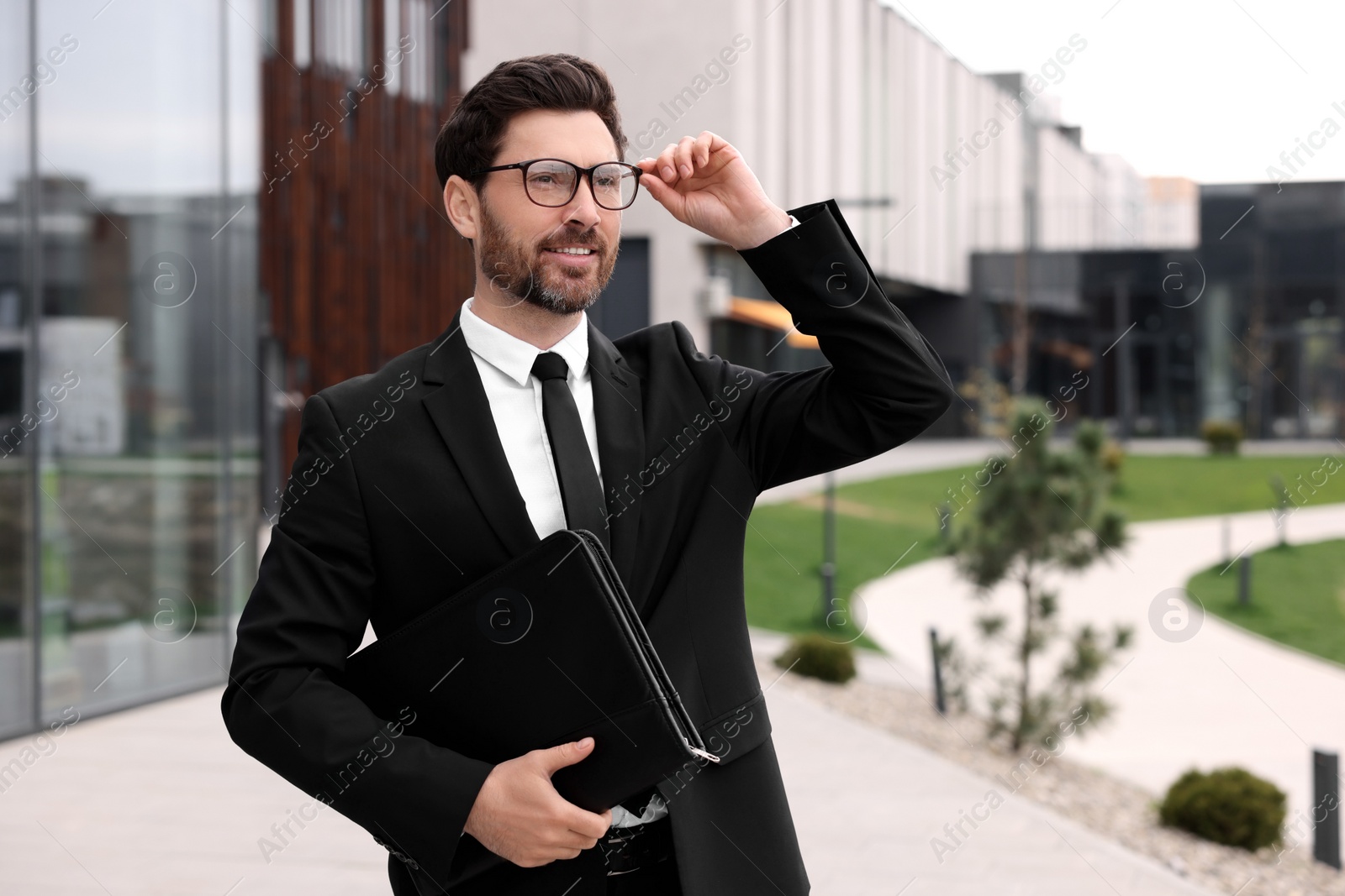 Photo of Male real estate agent with leather portfolio outdoors