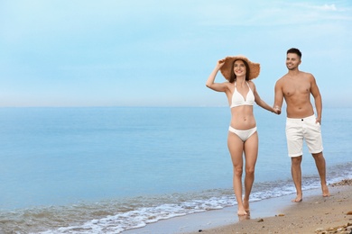 Photo of Young woman in bikini with her boyfriend on beach, space for text. Lovely couple