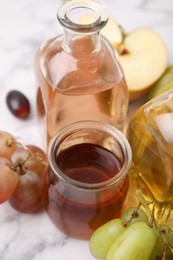 Photo of Different types of vinegar and ingredients on light table, closeup