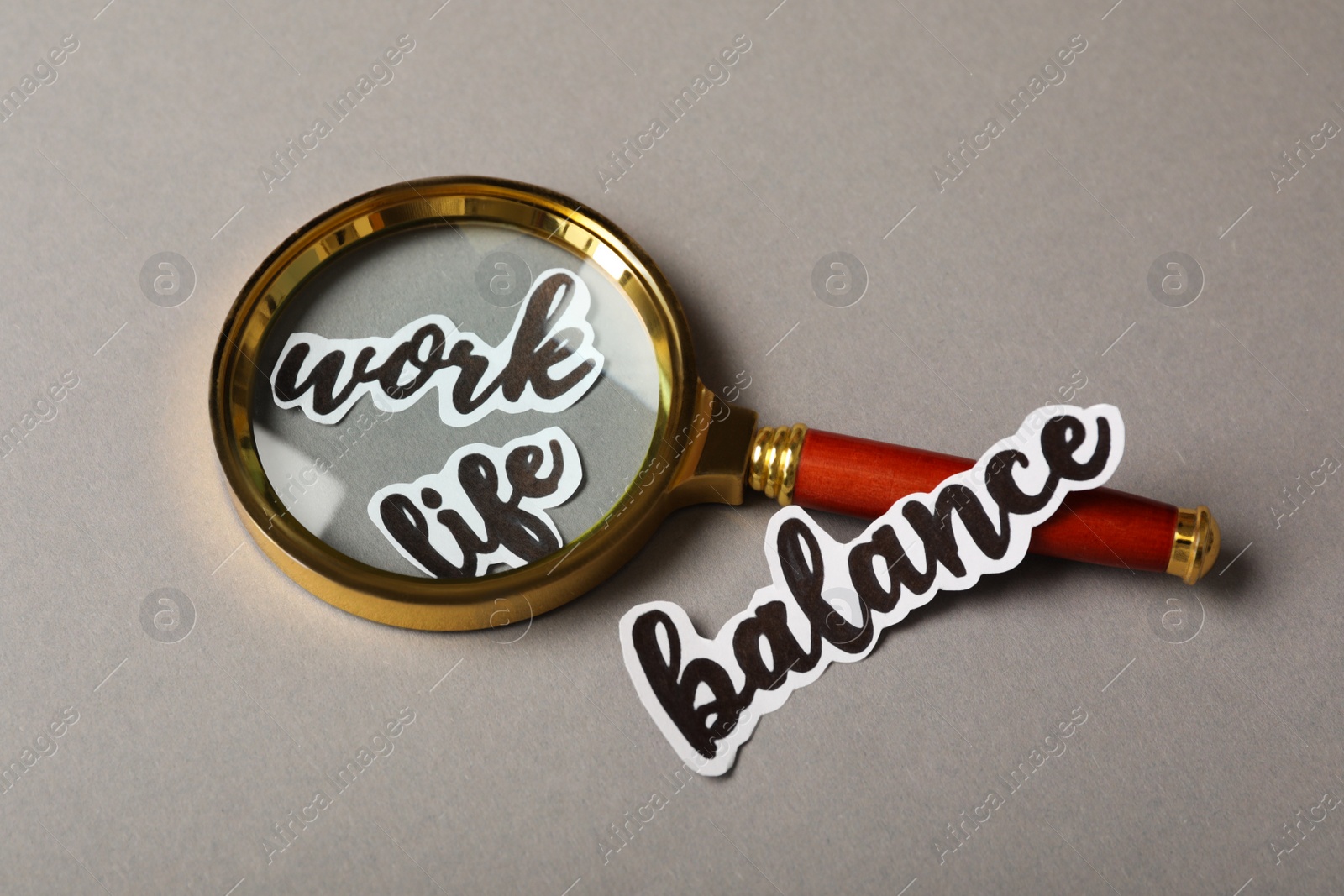 Photo of Magnifying glass on grey table. Life work balance concept